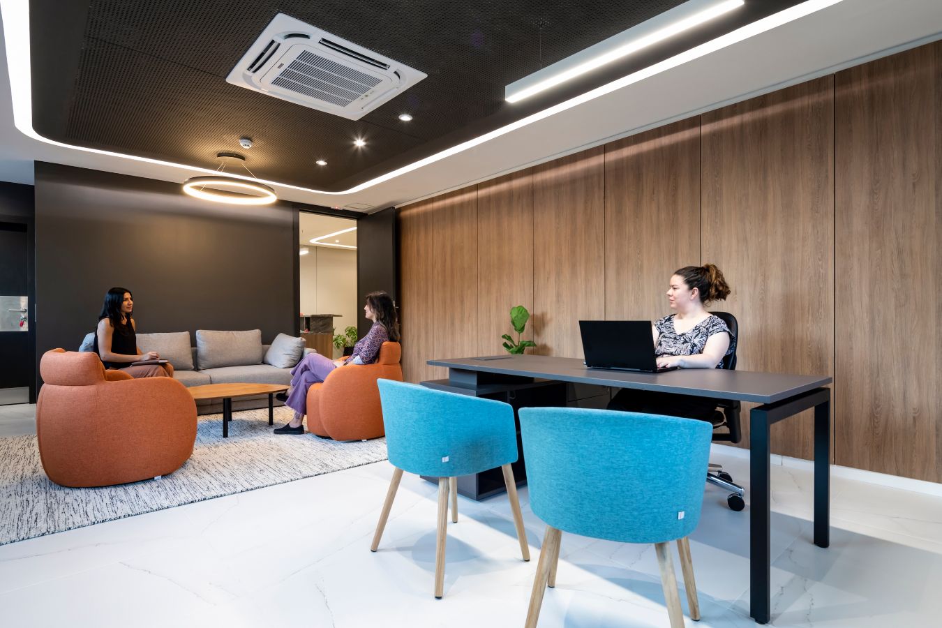 Aseguradora Yacyreta - Informal meeting lounge with warm wood paneling and blue accent chairs - Contract Workplaces.jpg
